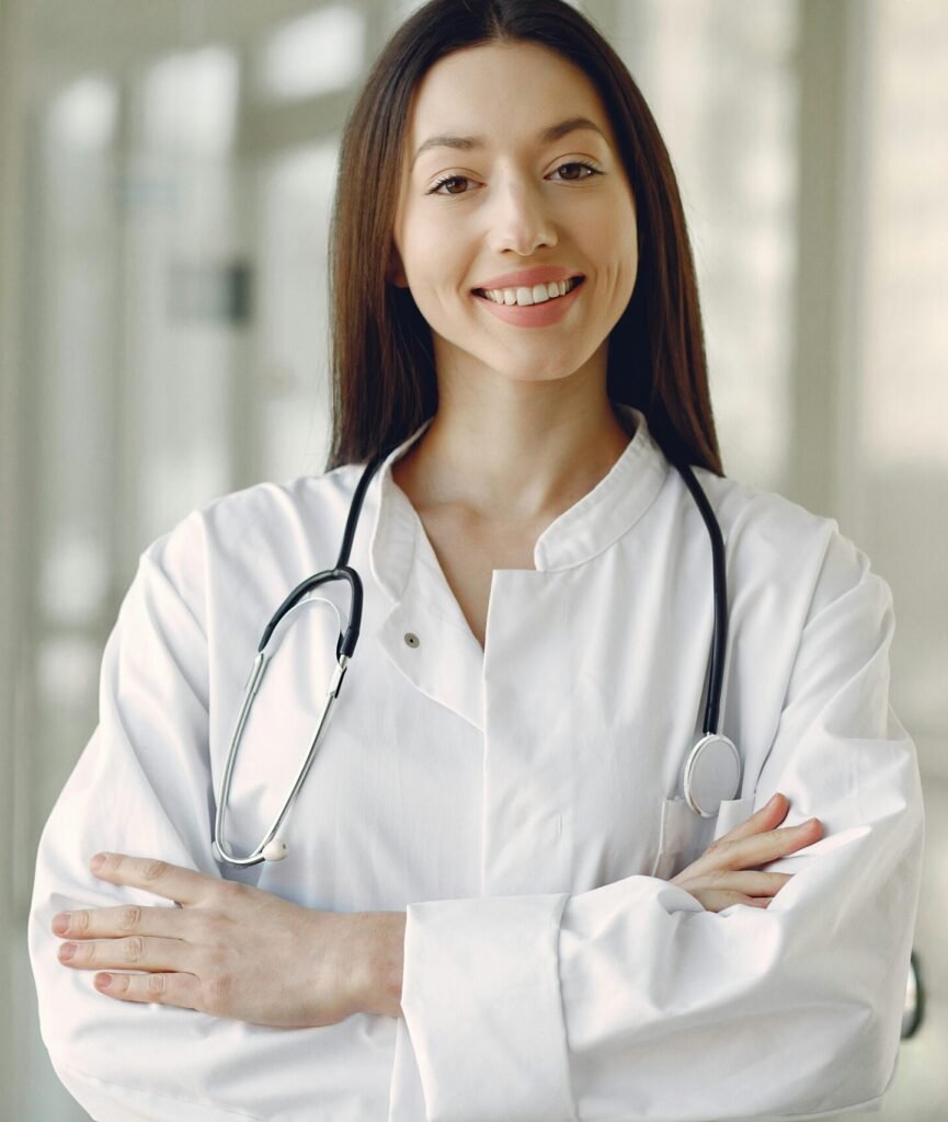 Portrait of a smiling female doctor with arms crossed and stethoscope in a hospital corridor.